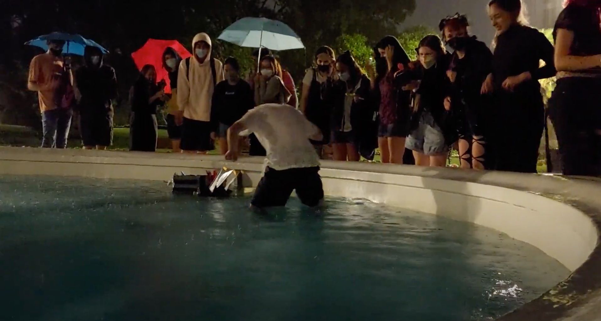 A maker club committee member jumping into a fountain to test out some duct-tape boats